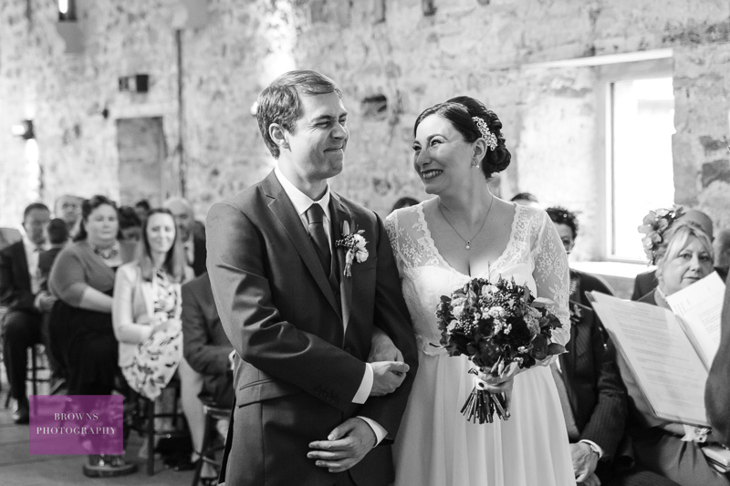 Bride and groom smiling during wedding ceremony at Healey Barn, Northumberland.