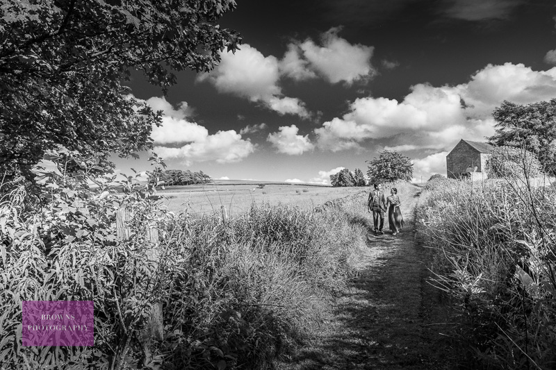 Bride and groom walking down country path at Langley Garden Station, Northumberland