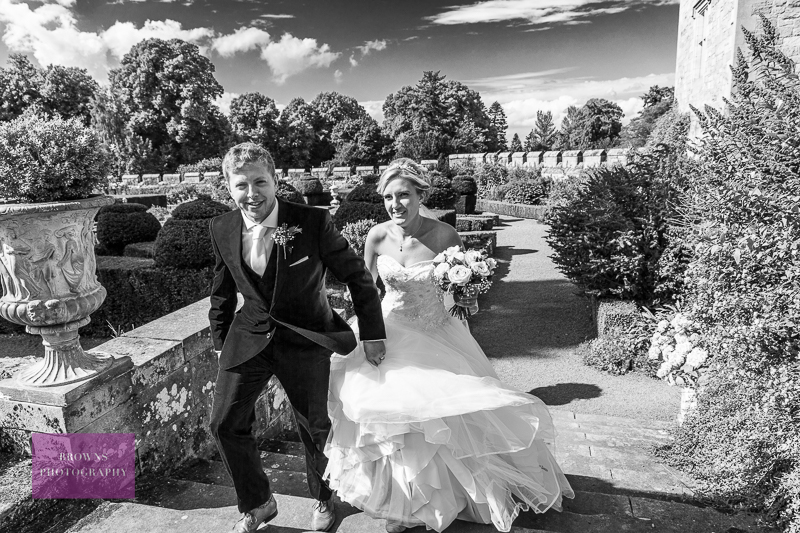 Bride and groom walking up steps in Chillingham Castle gardens