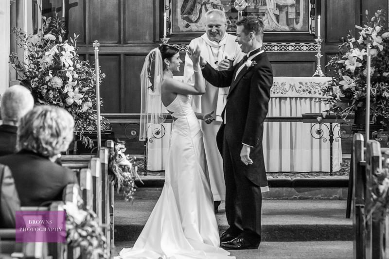 Bride and groom giving high fives in church before their reception at Ellingham Hall